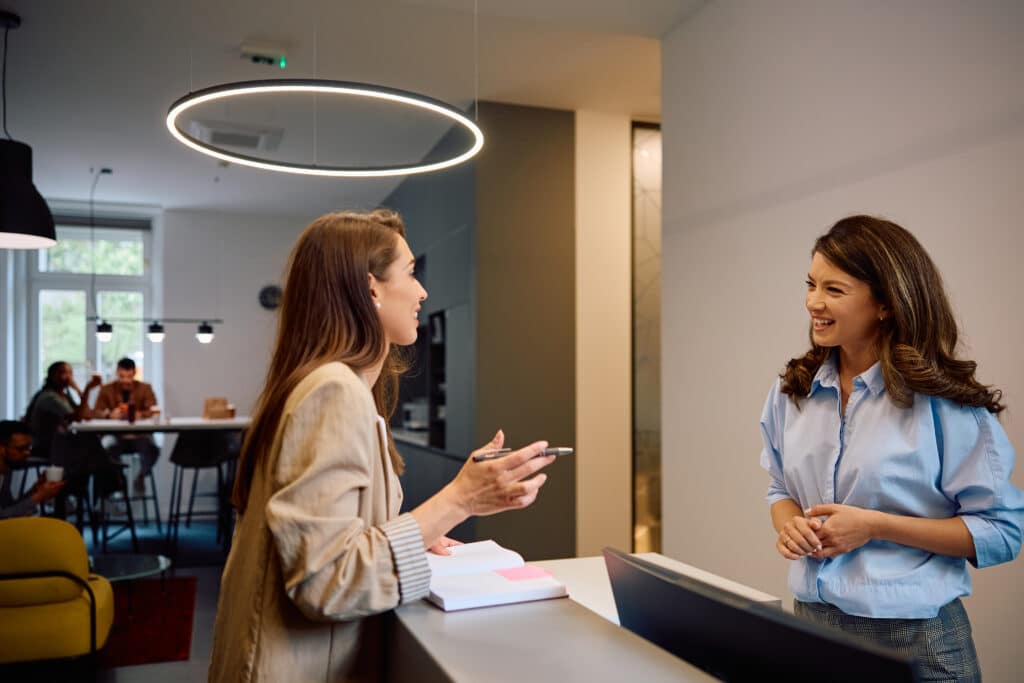 Happy female colleagues communicating while going through business notes in the office.